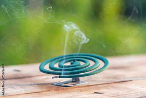 Smoldering mosquito coil in summer garden on wooden table, insect protection