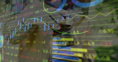 Overlaying candlestick bars and neon line graphs atop metallic knight helmet sculpture, workspace