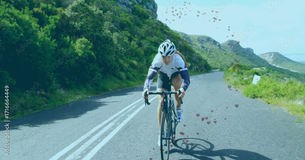 Obraz premium Riding solo female cyclist pedaling uphill on mountain road, with aerodynamic helmet and road bike