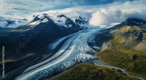 Majestic Glacier Flows Through Rugged Mountains Under Cloudy Sky at Noon.