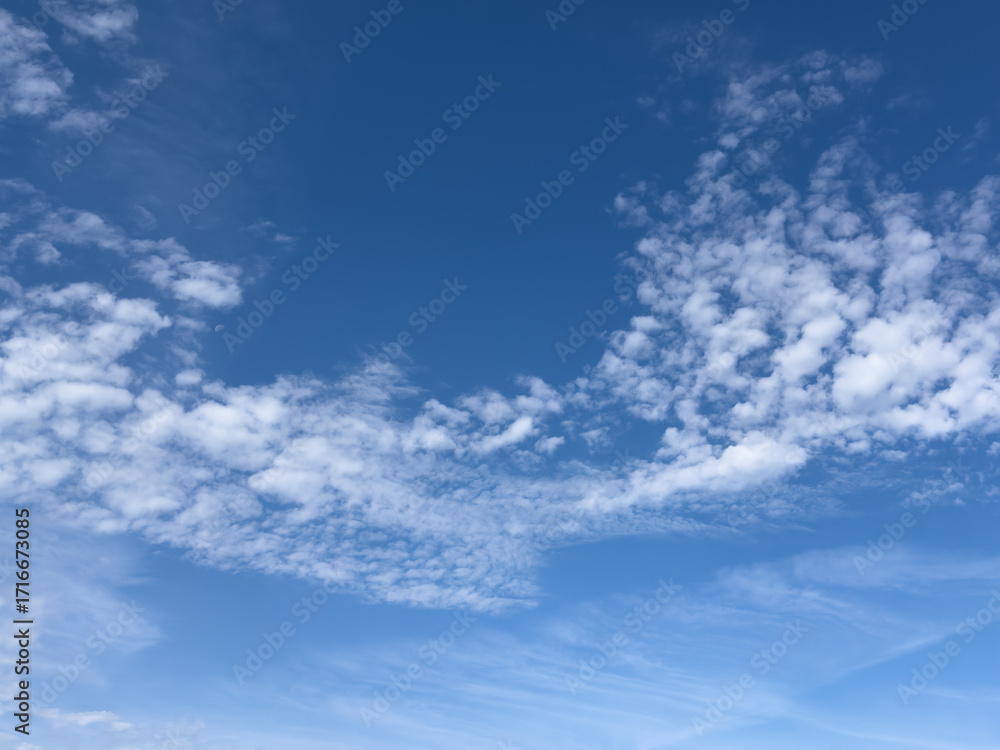 Obraz premium Soft bright blue sky with white few clouds. Calm texture. Nature abstract background. Fresh air, weather and freedom concept. Clear sky in the morning. The cloud float and clump like cotton.