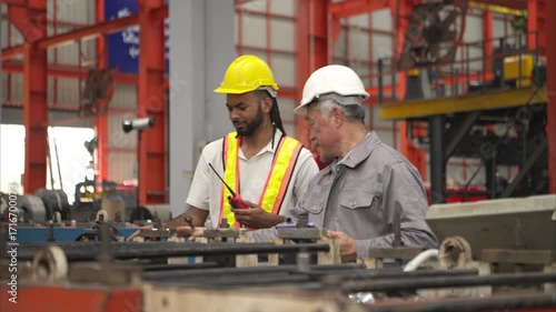 Wallpaper Mural Senior engineers and young man workers are talking and inspecting machines on a production line with safety helmets and other equipment Torontodigital.ca