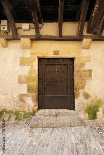 Porte ancienne marron entourée de pierre