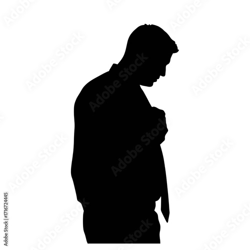 Silhouette of man adjusting tie while looking down in profile view  