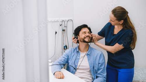 Audiologist conducts a hearing test using headphones in a modern clinic. Medical exam for hearing loss, deafness, audiology, healthcare.