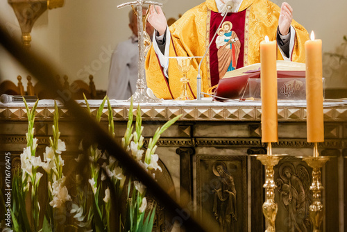 Catholic priest celebrating Holy Mass during liturgy with chalice, Bible, and liturgical vestments inside church, Eucharist and communion ceremony in Christian tradition