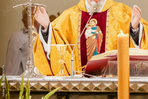 Catholic priest celebrating Holy Mass during liturgy with chalice, Bible, and liturgical vestments inside church, Eucharist and communion ceremony in Christian tradition