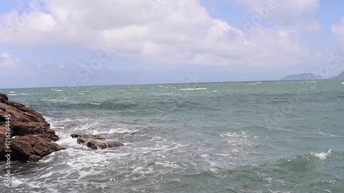 Gentle ocean waves breaking on the beach of São Sebastião, Brazil, with Ilhabela island in the background. Scenic coastal landscape in high definition