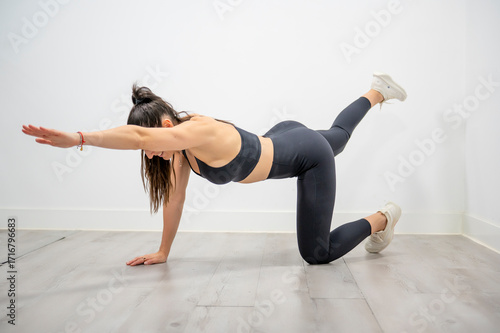 Woman practicing bird dog exercise extending opposite arm and leg in fitness training session