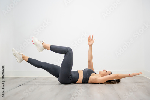 Woman performing dead bug exercise lowering opposite arm and leg for functional core training