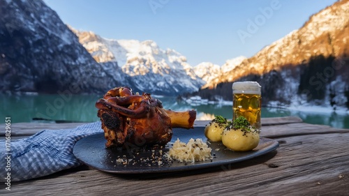 A stunning photo for a brewery or travel brand. A cinematic shot of a classic roasted pork knuckle and a pint of beer for a hearty winter holiday meal in a beautiful mountain landscape.