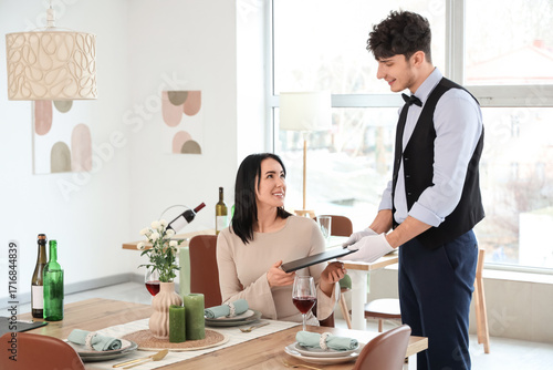 Male waiter giving menu to ...
