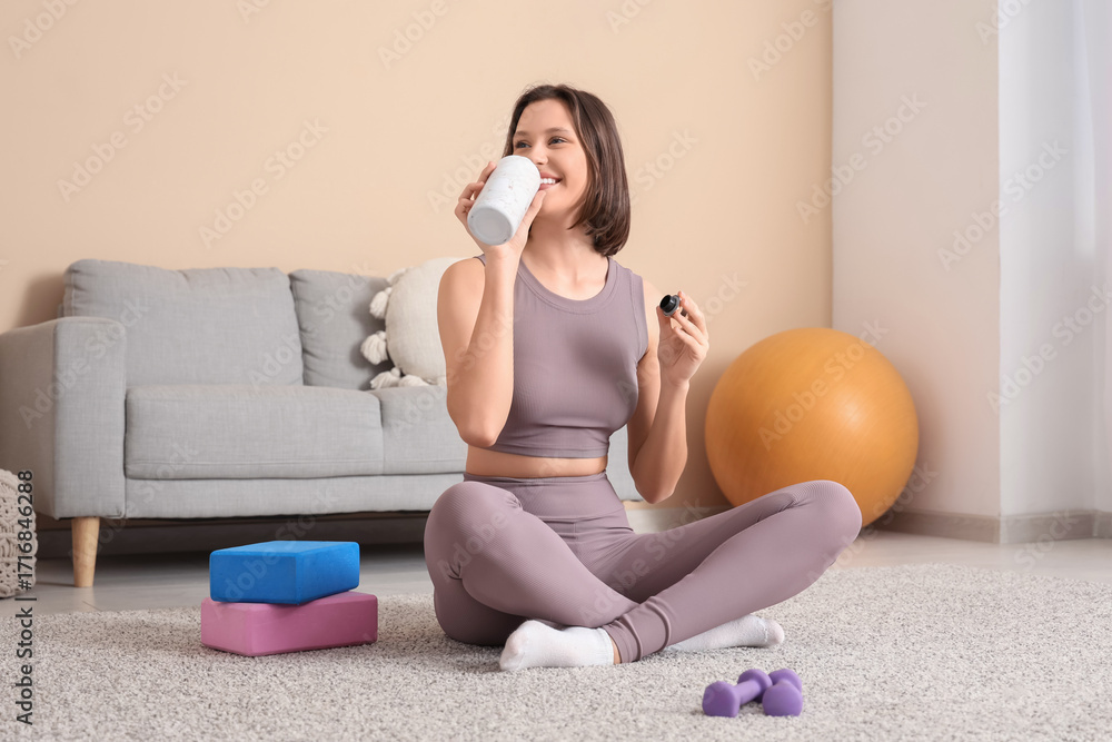 © Pixel-Shot - Sporty young woman drinking water on carpet at home © Pixel-Shot - Sporty young woman drinking water on carpet at home
