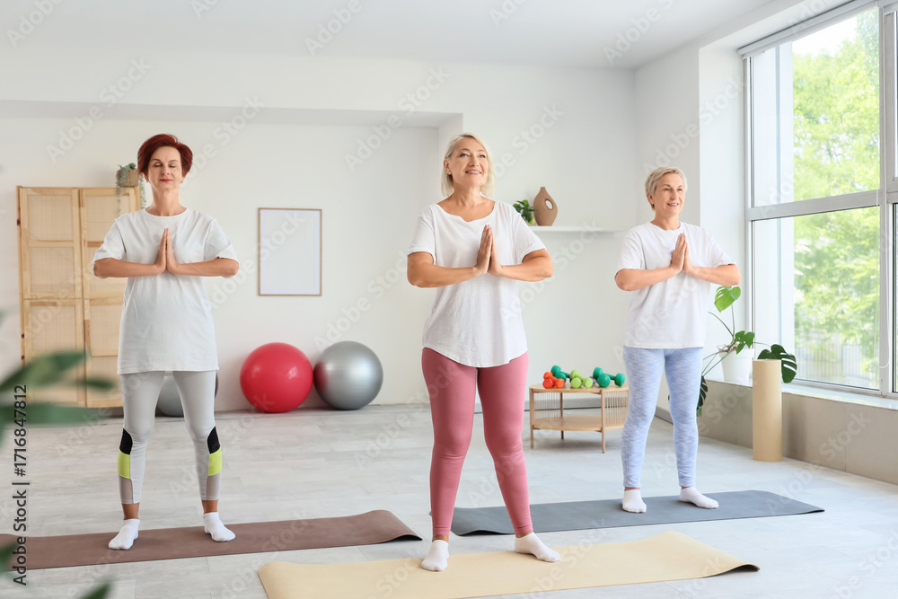 Naklejka premium Mature women practicing yoga at gym