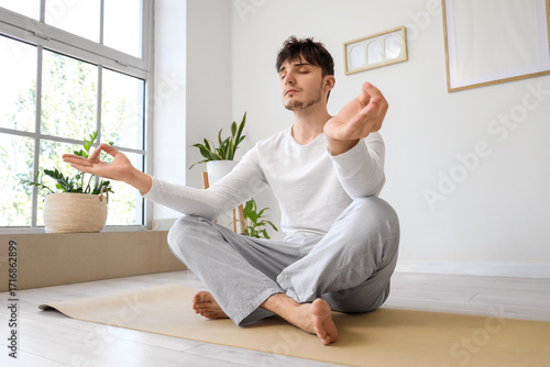 Young man meditating at home