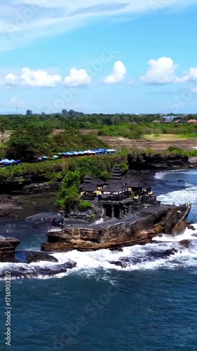 Aerial drone view of Pura Tanah Lot in Bali, Indonesia. It is an ancient Hindu pilgrimage temple, a popular tourist attraction, and a cultural icon.