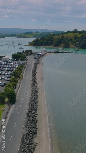 Wallpaper Mural Aerial view of a road leading to a pier and harbor in Sandspit, New Zealand. Cars are parked in a lot, and boats are docked in the water. The scene captures the coastal landscape. Torontodigital.ca