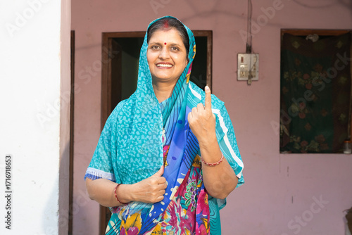 Fotografie Indian  mid aged rural woman standing in and showing their finger marked with blue ink after casting vote