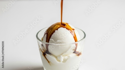 Espresso or syrup being poured over a scoop of vanilla ice cream in a glass.