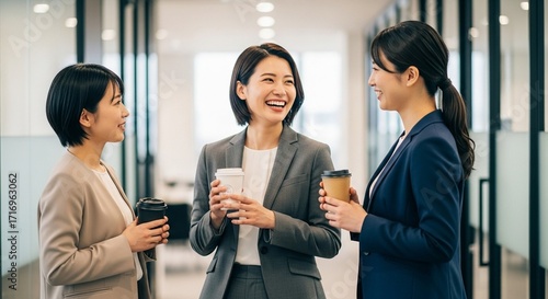 同僚との会話：オフィスの廊下で談笑する日本人女性社員たち