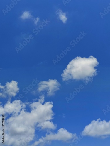 Bright blue sky with fluffy white clouds, perfect for background or nature concept.