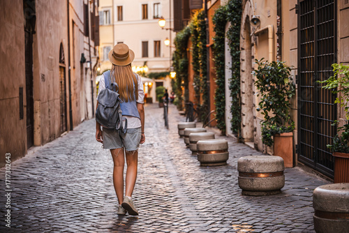 Photography Teenage girl with long hair in a straw hat and backpack walking along a charming
