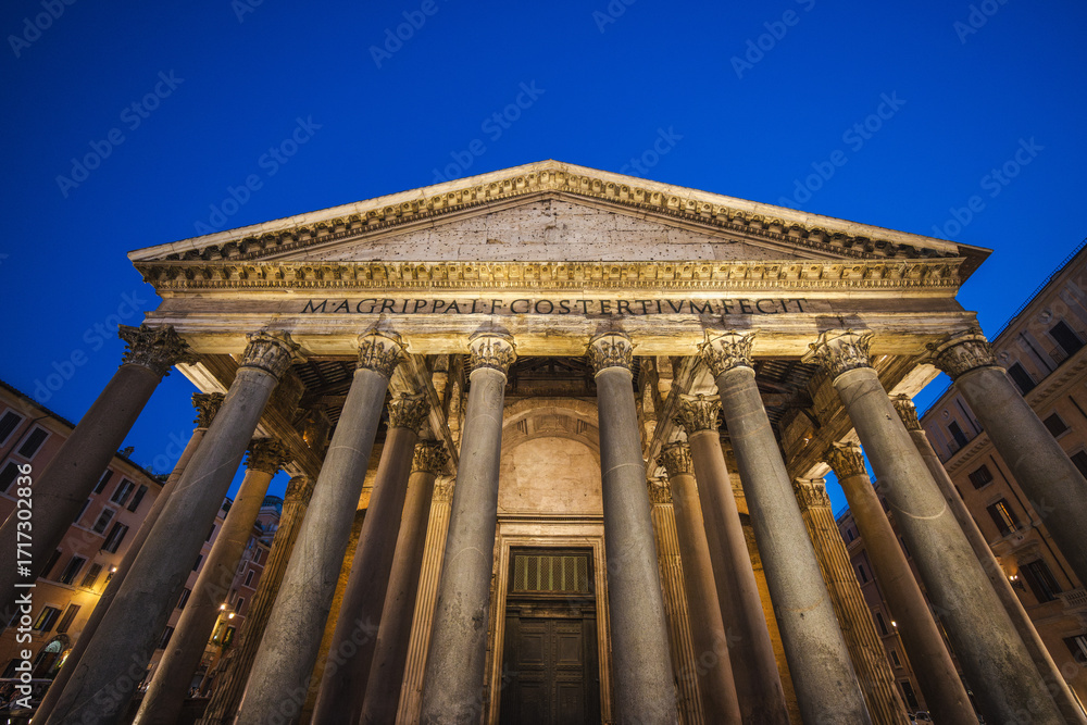 Fototapeta premium Pantheon in Rome illuminated at night with its grand columns and ancient inscription against a deep blue sky