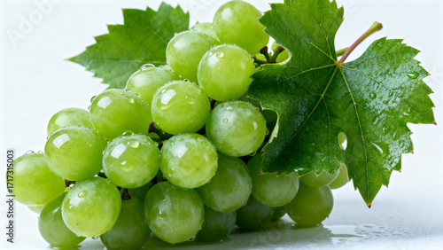 A cluster of fresh green grapes with water droplets and leaves on a white background