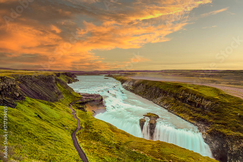 Golden hour view of Gullfoss waterfall in Iceland, October 2016, cascading white water through dramatic cliffs, colorful sky glowing above canyon, symbolizing iconic Nordic travel landscape.