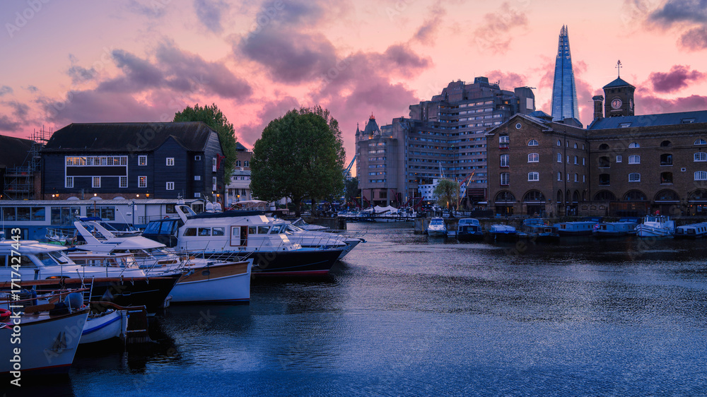 Naklejka premium Tranquil twilight seascape at St Katharine Docks Marina, built in the 1820s on the River Thames, now a vibrant waterside hub with boat berths, shops, restaurants, and residences in central London.