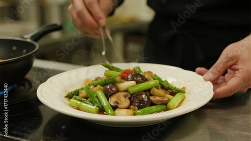 Wallpaper Mural A chef plates a stir-fried dish with asparagus, mushrooms, and vegetables in a kitchen setting. Torontodigital.ca