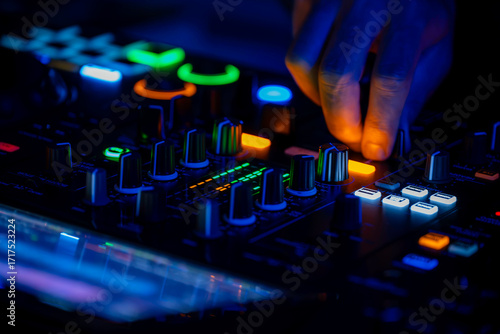 DJ hands mixing on console at night with colorful club lights. Party life, youngsters having fun.