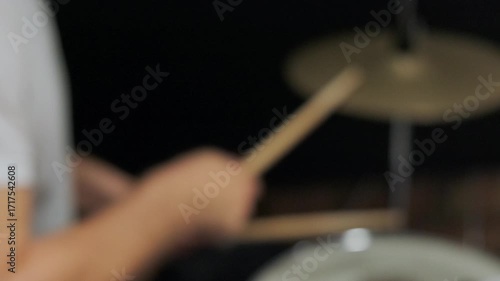 Man drummer hits drum kit in dark music studio. Creates music and art. Drum set, drummer plays on drums. The rock band is rehearsing, studying or recording song. The musician is playing in slow motion