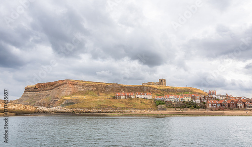 A seaside panorama with a church on a hill and houses beneath.