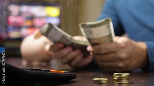 Close up view of man hands, calculator, Indian rupee coins and banknotes (INR). Concept of saving money for retirement, cash settlement, financial goals, success, literacy and income planning in India
