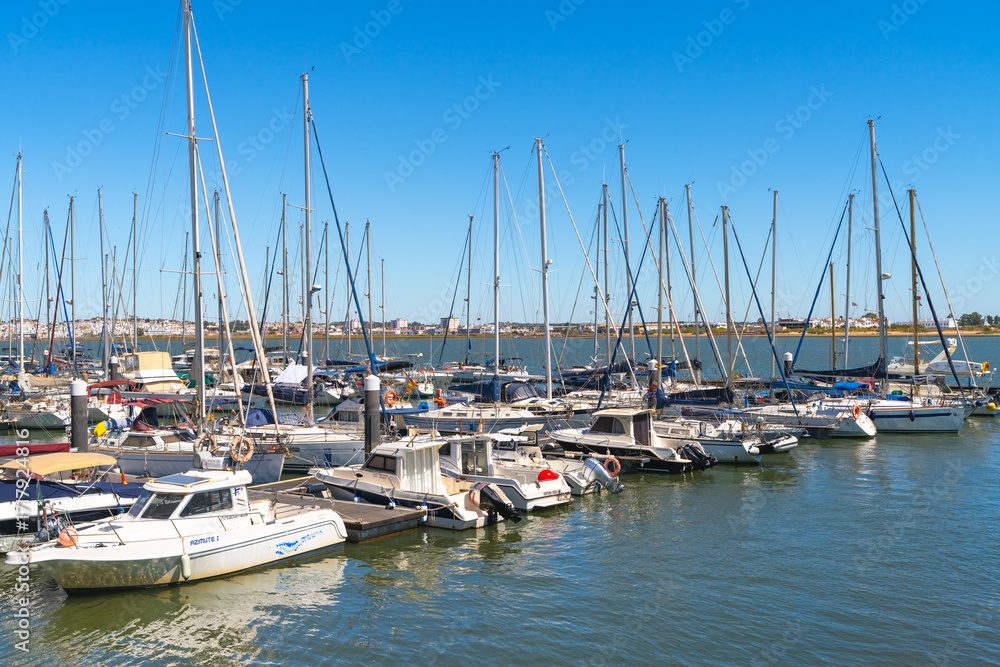 Fototapeta premium Dozens of sailboats and yachts are moored in a marina under a bright blue sky in Vila Real de Santo Antonio.