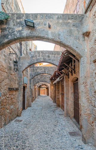 Narrow cobblestone alley with stone houses in the medieval old town of Rhodes, Dodecanese, Greece.