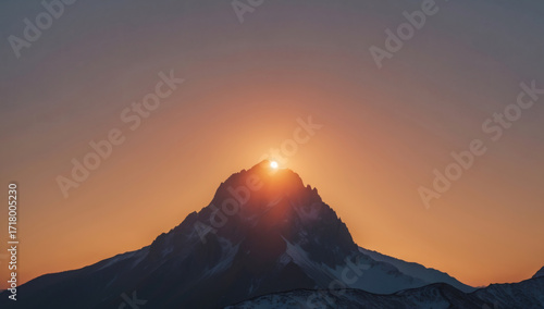 Sun rising behind mountain peak, minimalist silhouette with glowing sky