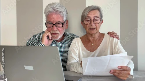 Video call concept. Elderly couple sitting at home talking remotely with doctor on mobile phone webcam to communicate the results of some medical tests,  waits for doctor's consultation