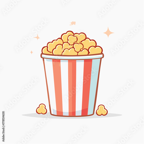 A bucket of popcorn with red and white stripes, with a few kernels scattered around.