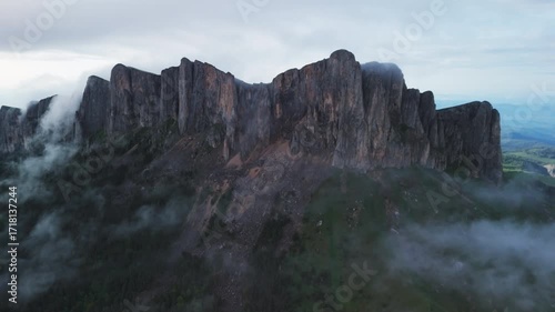 Scenic aerial view of Bolshoy Tkhach mount with clouds and evening sunlight.