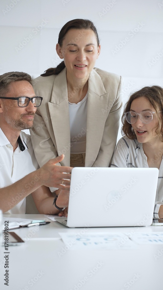 Obraz premium Business people working together, reviewing data on laptop screen, sharing insights during collaborative office meeting, emphasizing professional teamwork