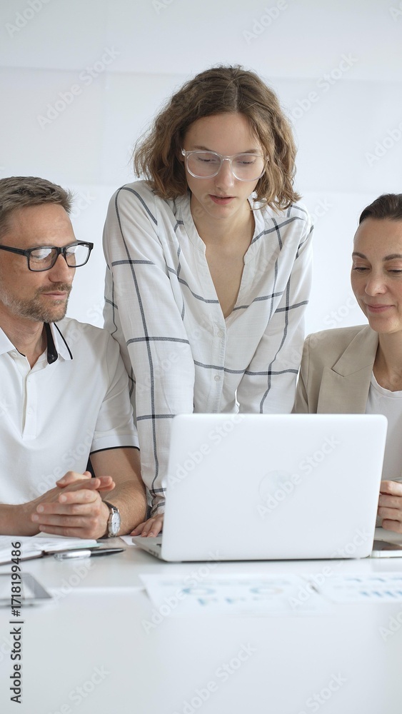 Fototapeta premium Business people team collaborating on a project, analyzing data on a laptop during a productive office meeting, fostering teamwork and strategic planning