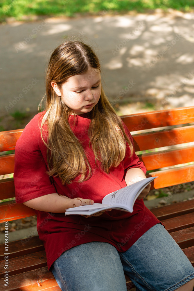 Obraz premium Girl reading a book on a park bench