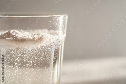 Creatine monohydrate powder dissolving in water glass close up