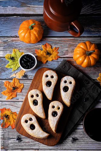 Linzer cookies in the form of ghosts for Halloween holidays on a wood background