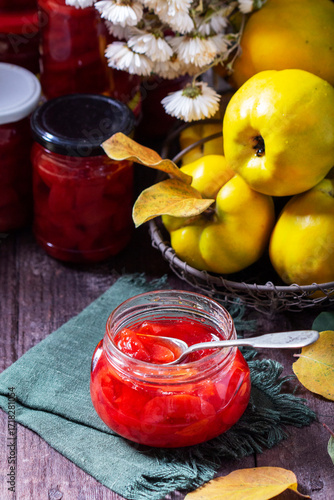 Quince jam in a glass jar, quince in a basket and a bouquet of chrysanthemums. Autumn still life.