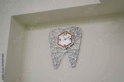 A tooth-shaped clock in a dental clinic. An interesting watch as a gift to the dentist. Stylish accessories for the dental clinic.