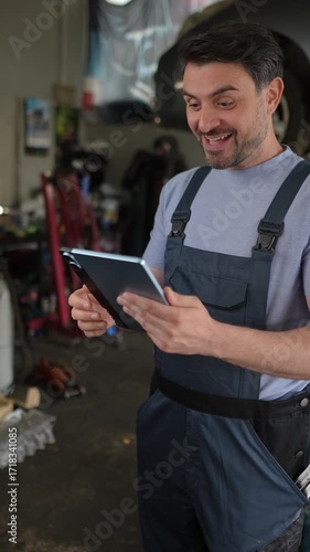Happy mechanic receiving good news on a tablet in a garage
