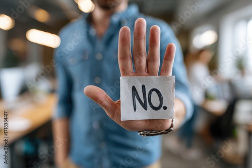 A Close-Up of a Person Holding a Sign Saying 'No', Emphasizing Rejection or Dissent in a Modern Office Environment